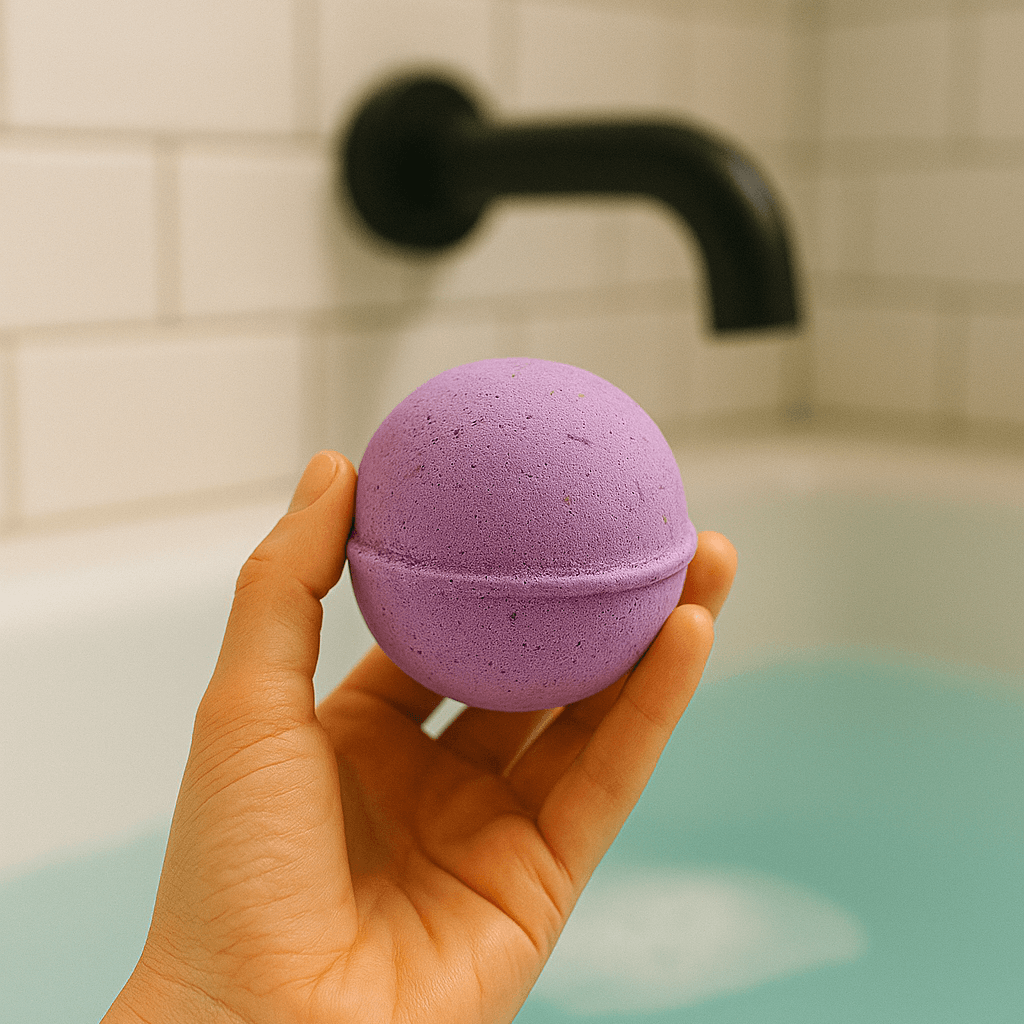 Hand holding a purple CBD bath bomb above a soothing turquoise bath.