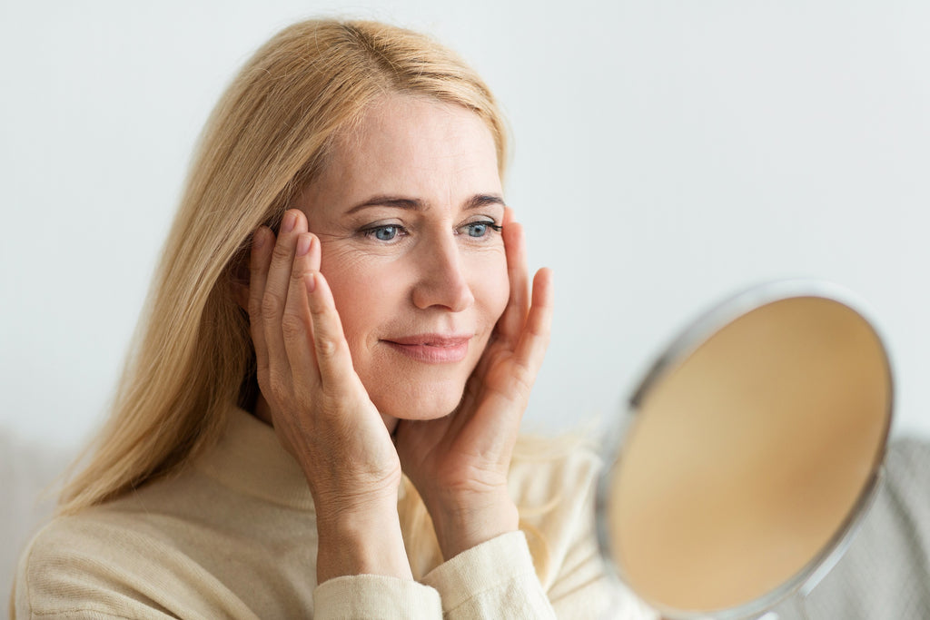Woman looking at mirror while touching her face